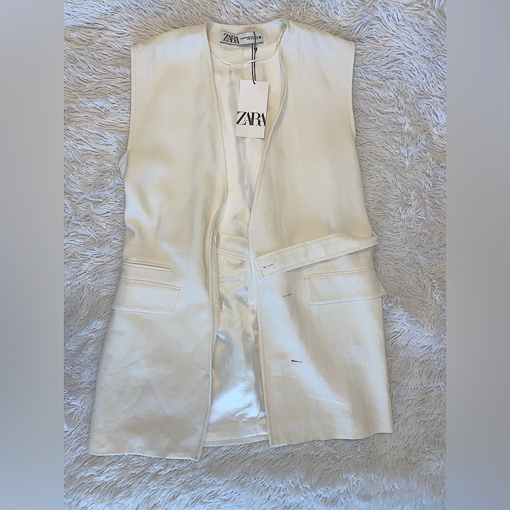 Cream vest w/ adjustable belt, buttons, & pho-pockets.